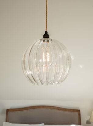 Hereford ribbed glass light fitting suspended in a bedroom, a true example of designer pendant lighting by Fritz Fryer.
