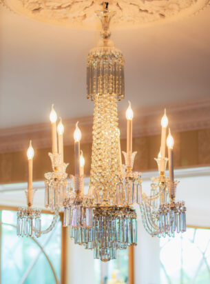A large Antique chandelier suspended from a decorative ceiling rose.