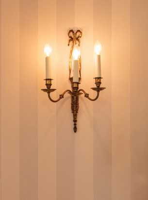 3 branch antique wall sconce restored by the Fritz fryer restoration team, installed on a striped wallpaper wall.