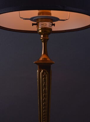 antique brass table lamp with pretty decoration and light emitting from the fabric lampshade