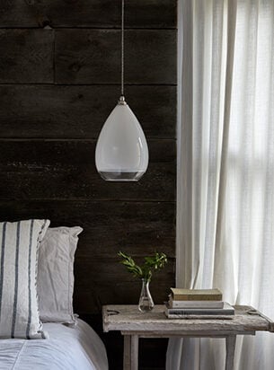 Modern bedroom with dark wood headboard, featuring a contemporary pendant light over the bedside table.