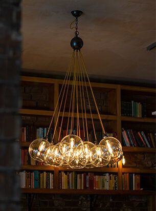 A chandelier made from glass globe shades and hung in a restaurant in front of book shelves