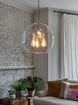 Stunning globe lantern hung in a sitting room, this large hand blown glass shade makes a superb feature with the brick wall background