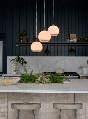 3 globe pendant lights over a kitchen island with white and clear glass globe shades over a bowl of lemons