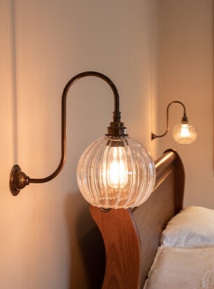 Two swan neck globe wall lights set either side of a bed make perfect reading lights for a bedroom.