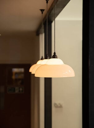 Office pendant lights hung in a line of 3 with white glass shades