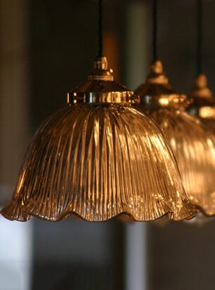 A row of three Holophane vintage ceiling lights featuring a nickel and black cotton pendant set.