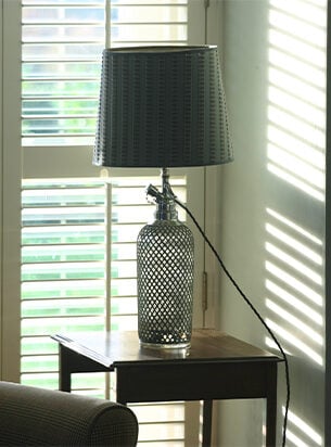 A converted soda syphon table lamp situated on a side table next to an armchair, a perfect example of how practical vintage table lamps can be.