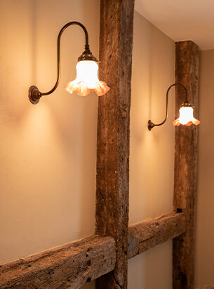A pair of vintage wall lights creating a cosy atmosphere within a farmhouse hallway.