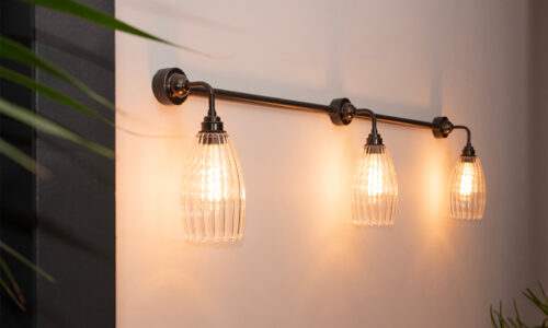 Wall lights on a conduit bar in a row with ribbed glass shades making perfect office lighting