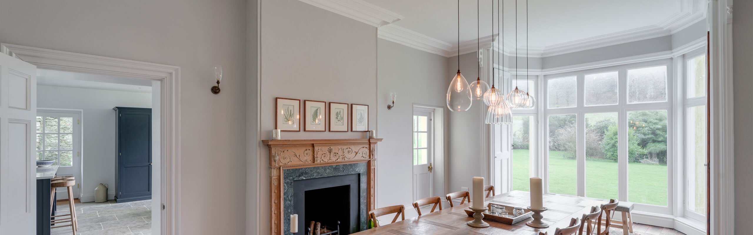 A home with a selection of dining room lighting ideas featuring, pendant lights over the table and wall lights beside the fireplace.