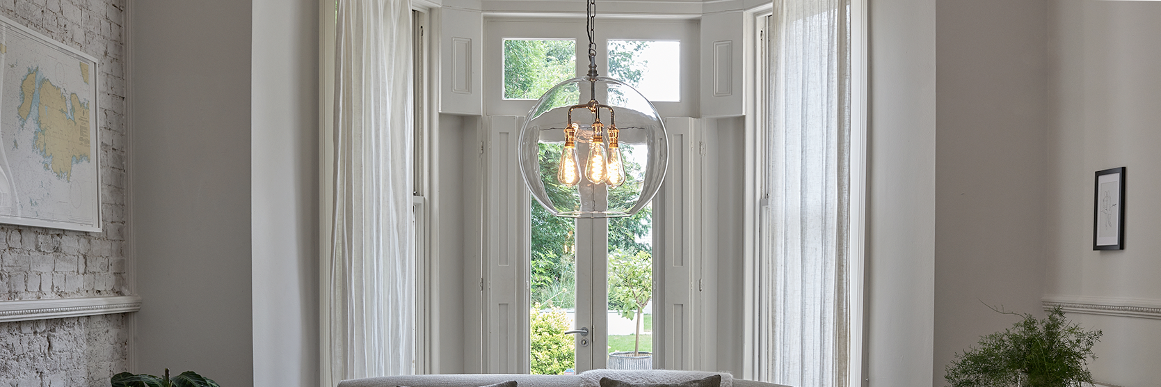 Clear glass globe lighting. featured within a light and airy living room setting.