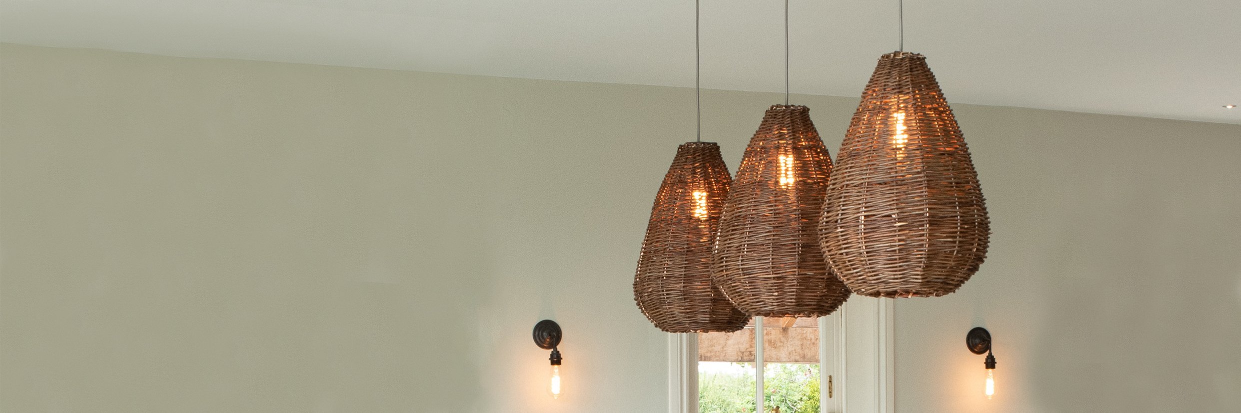 Three wicker pendant lights featured within a stylish kitchen, perfect for adding a touch of scandi lighting to homes and commercial spaces.